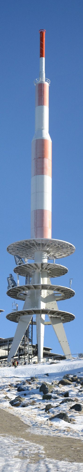 Brocken Fernmeldeturm mit rot-weißer Markierung, umgeben von Schnee und klarem Himmel.