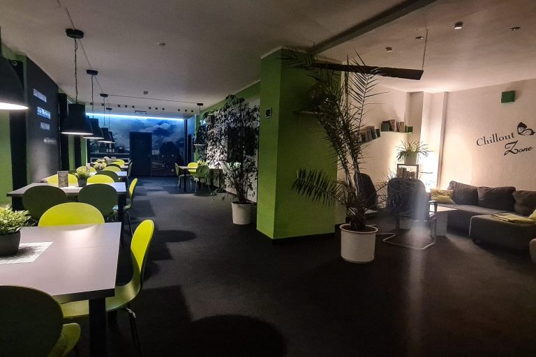 Loungebereicht mit Couch Moderne Lounge Umgebung mit grünen und schwarzen Elementen sowie Pflanzen und Sitzbereichen.